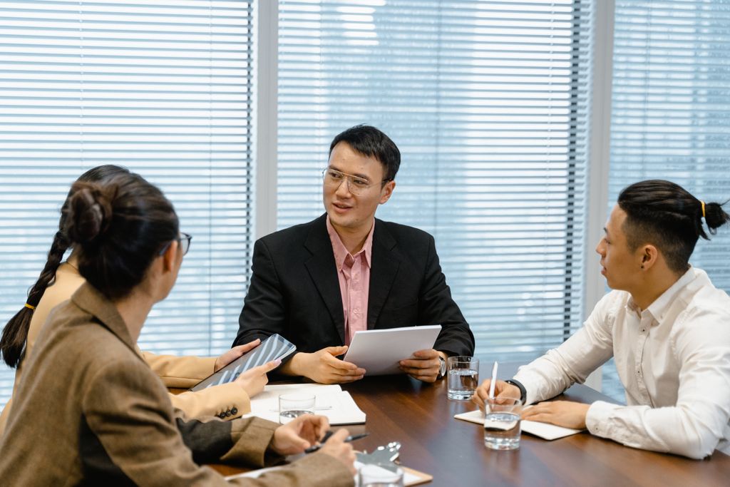 A group of business professionals having a discussion during a meeting in a modern office setting.